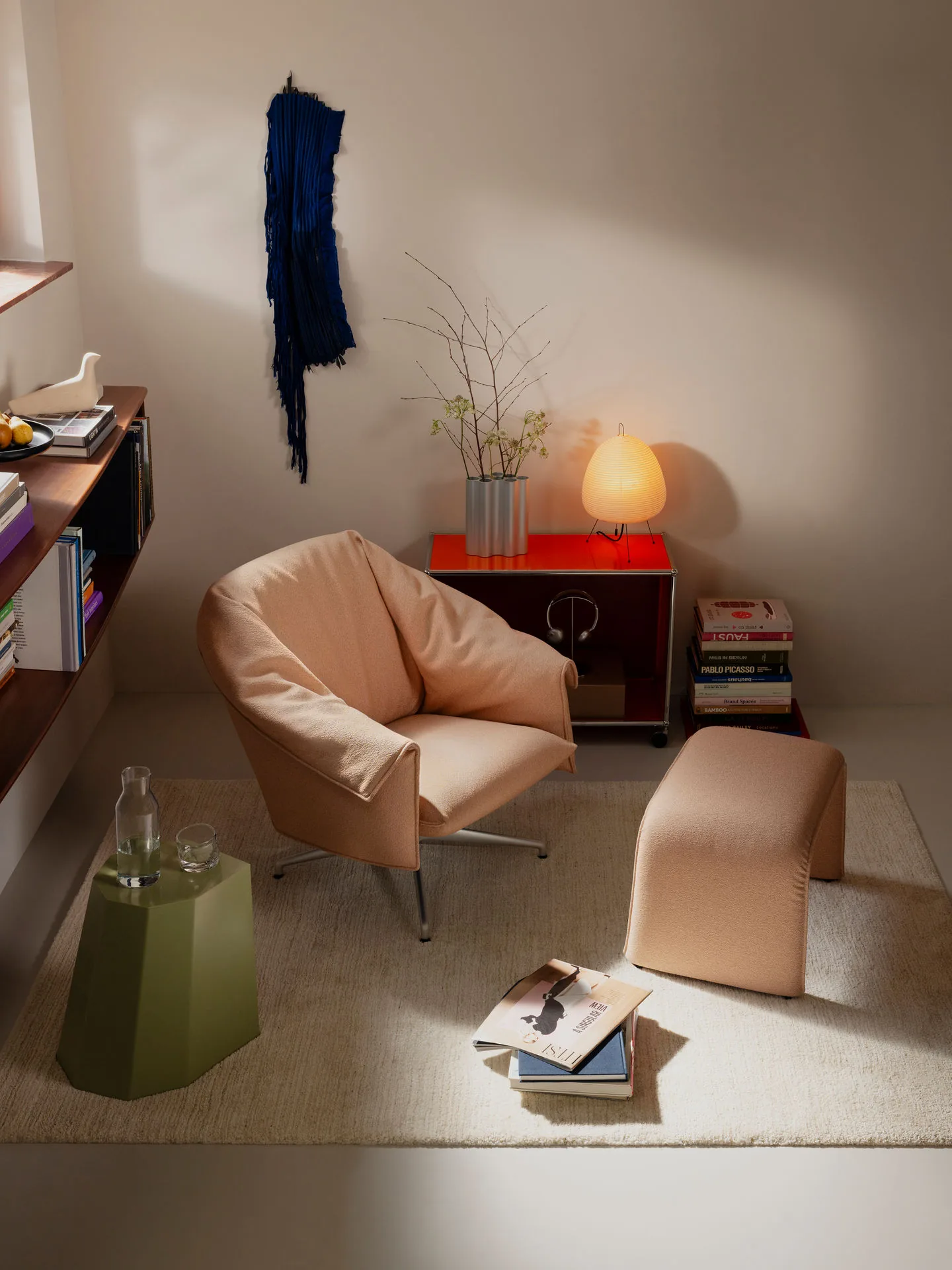 Vitra Loungesessel Bascule in pfirsichfarbenem Stoff mit Ottomane neben Sideboard und Leuchte
